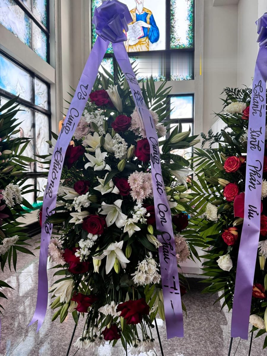 Standing spray of red roses, white lilies, and pink mums with a lavender ribbon.